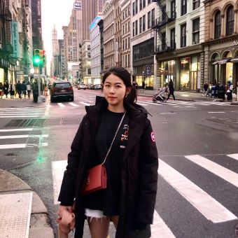 Rebecca (Jinye) Li stands in front of a busy city street