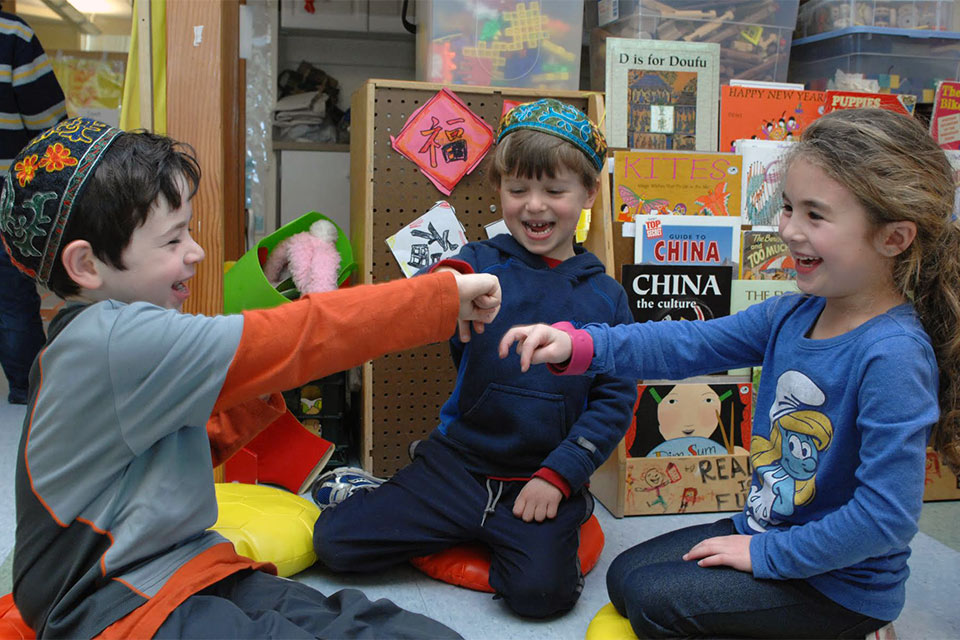 Three small children playing together in a classroom.