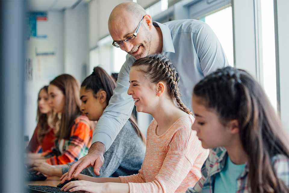 High school students receive help from a teacher during a lesson