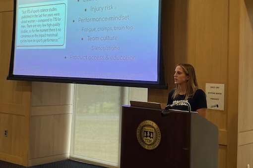 Ava Ferrigno standing behind a podium speaking to a group of students