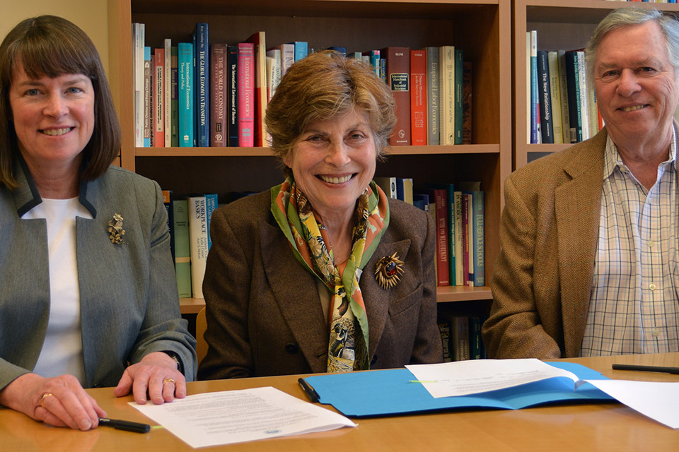 provost and husband and wife benefactors signing papers while seated at table.