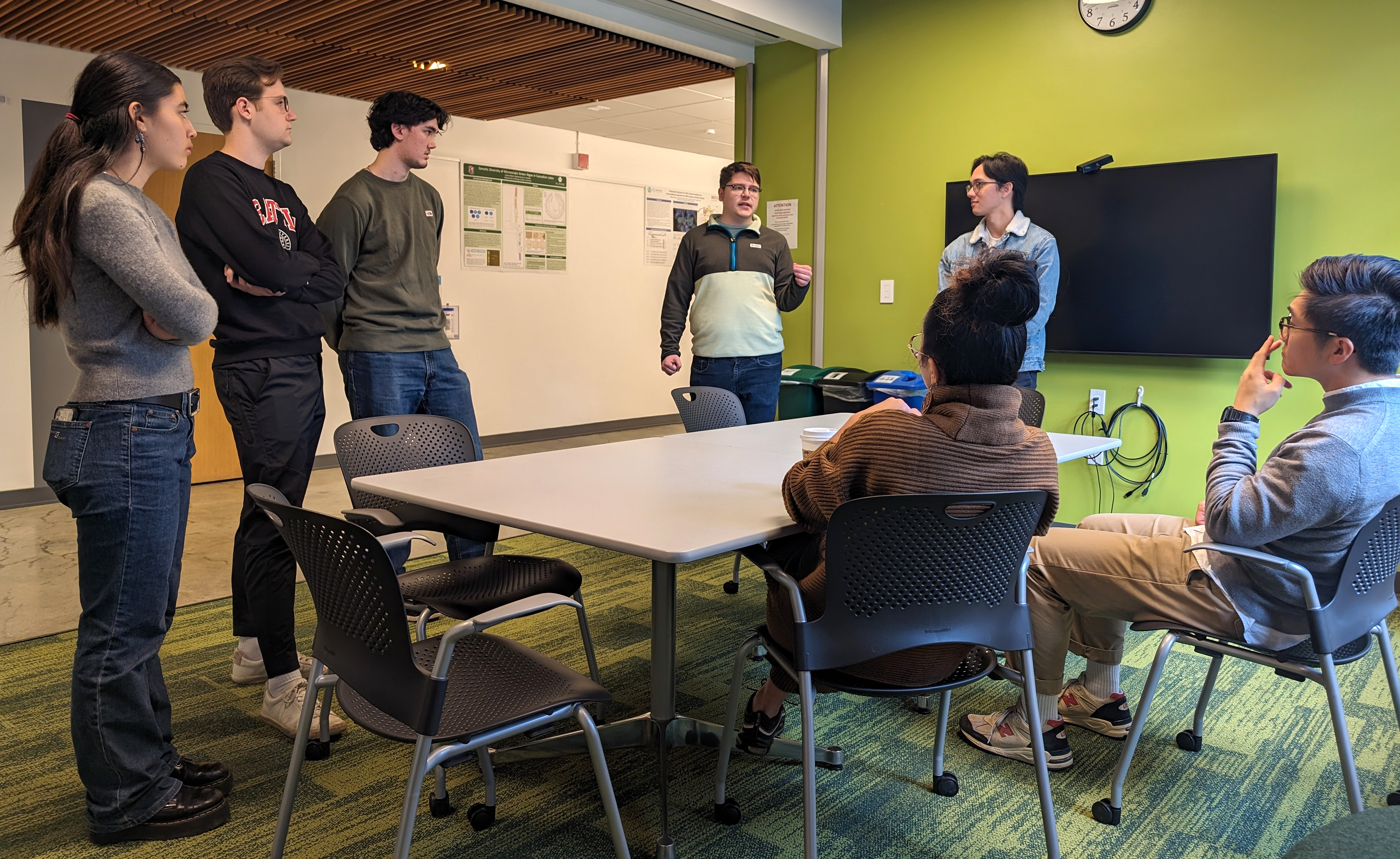 photo of students presenting in front of a classroom with a slide projected on screen