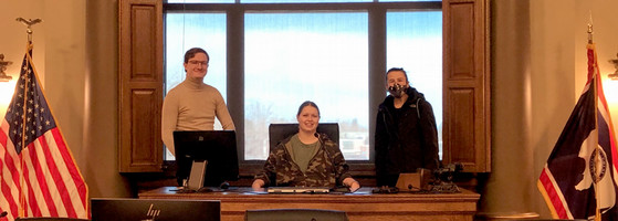 ENACT Faculty Fellow Lily Rowen with two students at a formal desk at the Wyoming State Capitol in the 2021-22 academic year