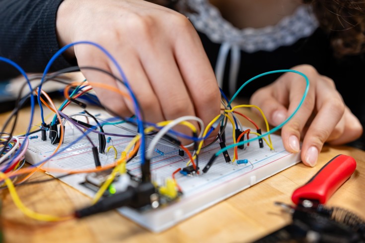 Hands working on a breadboard electronics prototype