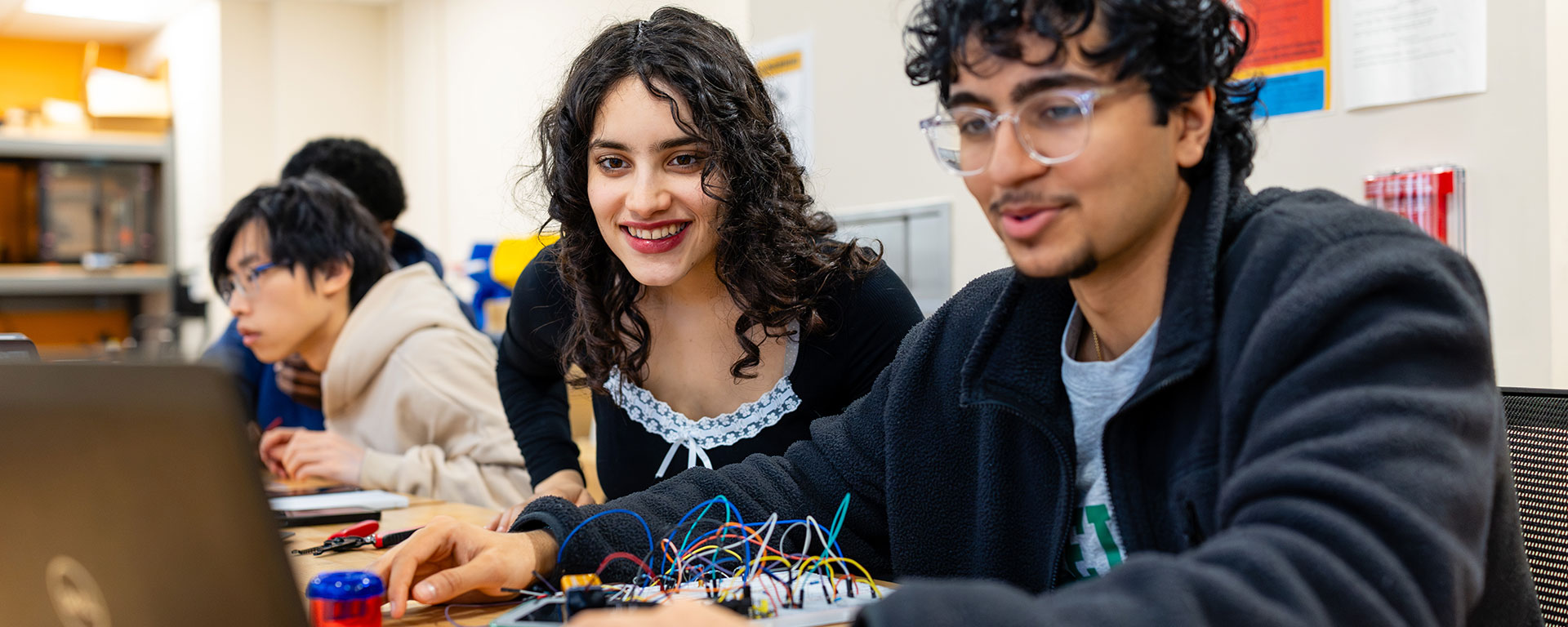 Two engineering students look at a laptop screen together.
