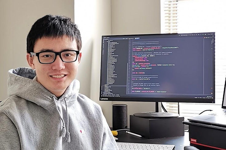 hangyu du, sitting in front of computer that displays lines of code 