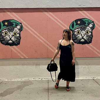 Larissa Cvatch standing in front of a cat mural