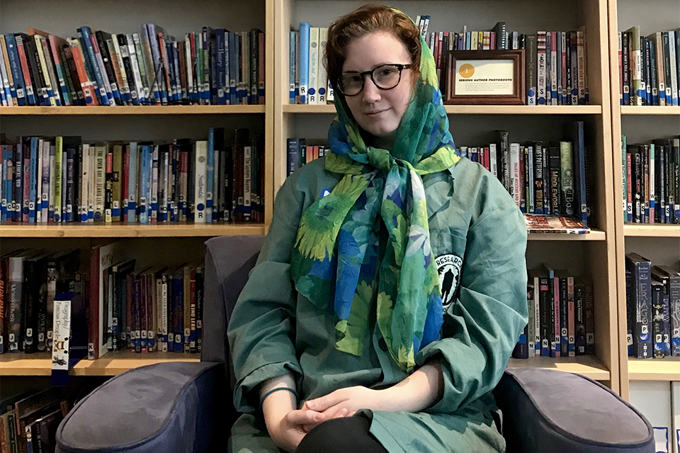 Cara DuBois seated in front of bookshelves