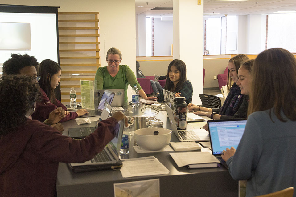 students at their computers work collaboratively in a circle.