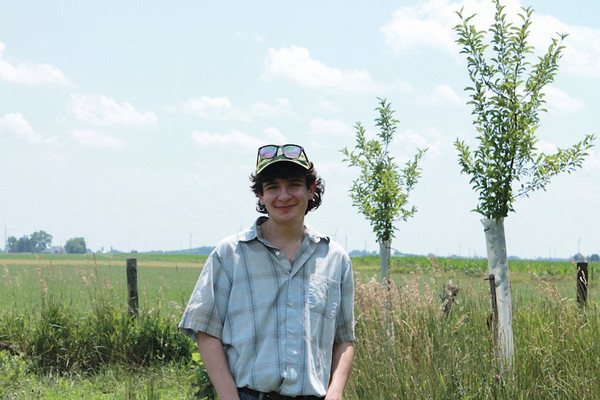 Daniel on the farm with two young apple trees