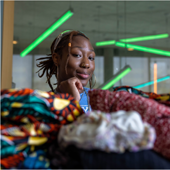 Mazzi Ingram sits behind a pile of colorful clothing