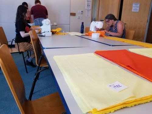 Faculty and student sew fabric together on sewing machines