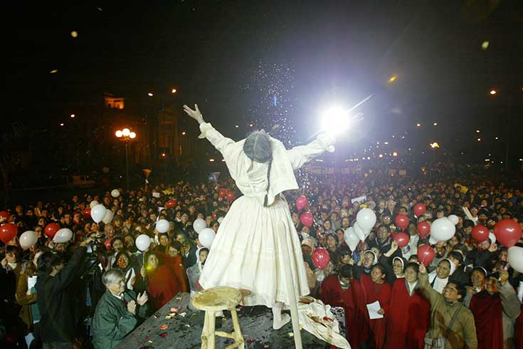 A performer with hands raised looking out at the audience