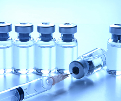 a syringe and several vials of vaccine