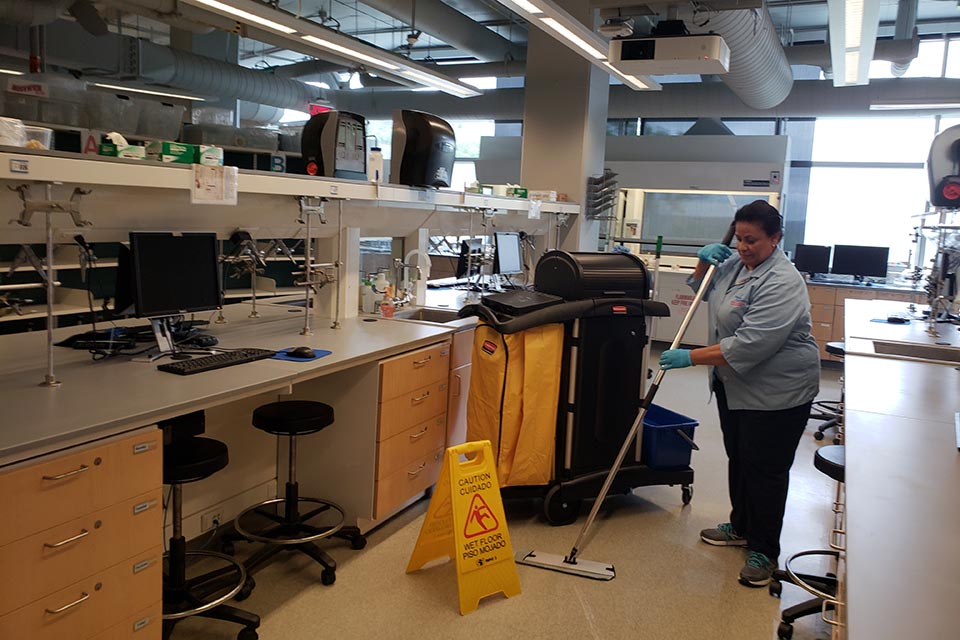 Facilities staff at work: Woman mopping the floor in a lab.
