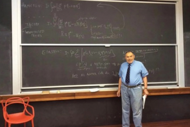 Stanley Deser stands in front of a chalkboard in a classroom
