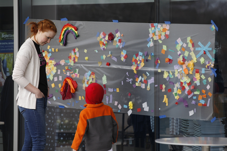 Student teaching child at an activity at festival of the arts