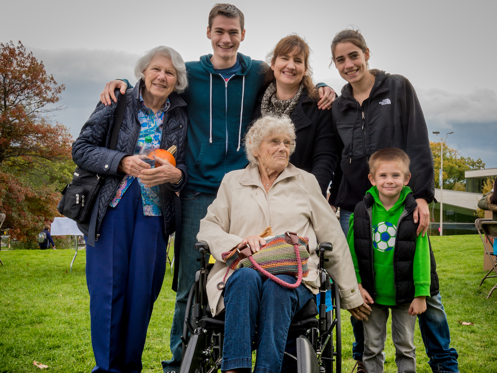 Parents, college aged child, younger child and grandmother in a wheelchair pose at Fall Fest