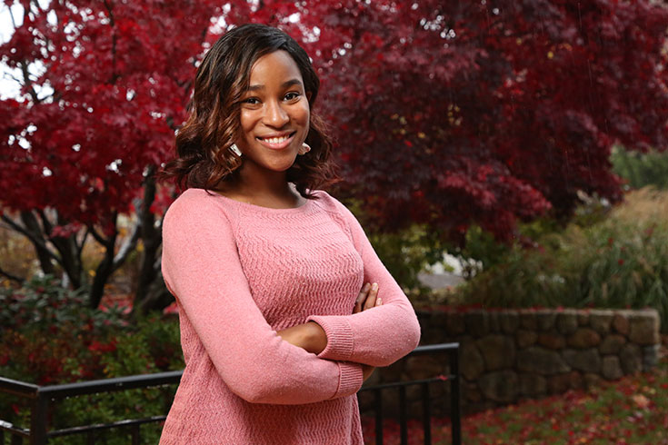 Minnie Norgaisse smiling in front of a red tree