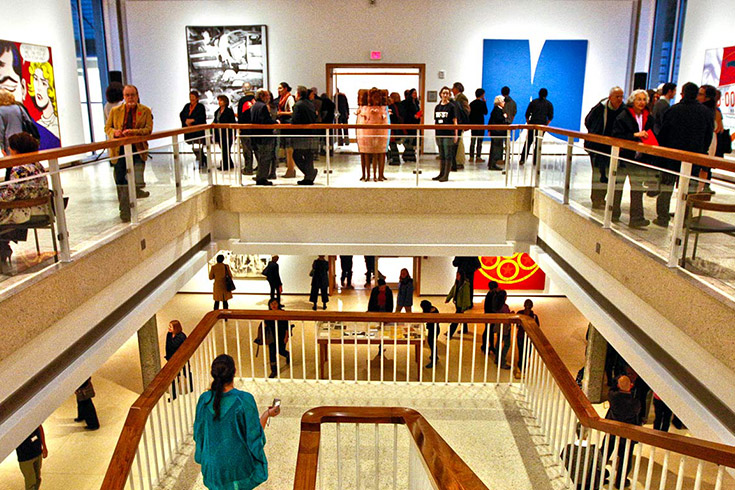 People viewing art inside the Rose Art museum with the staircase in the middle