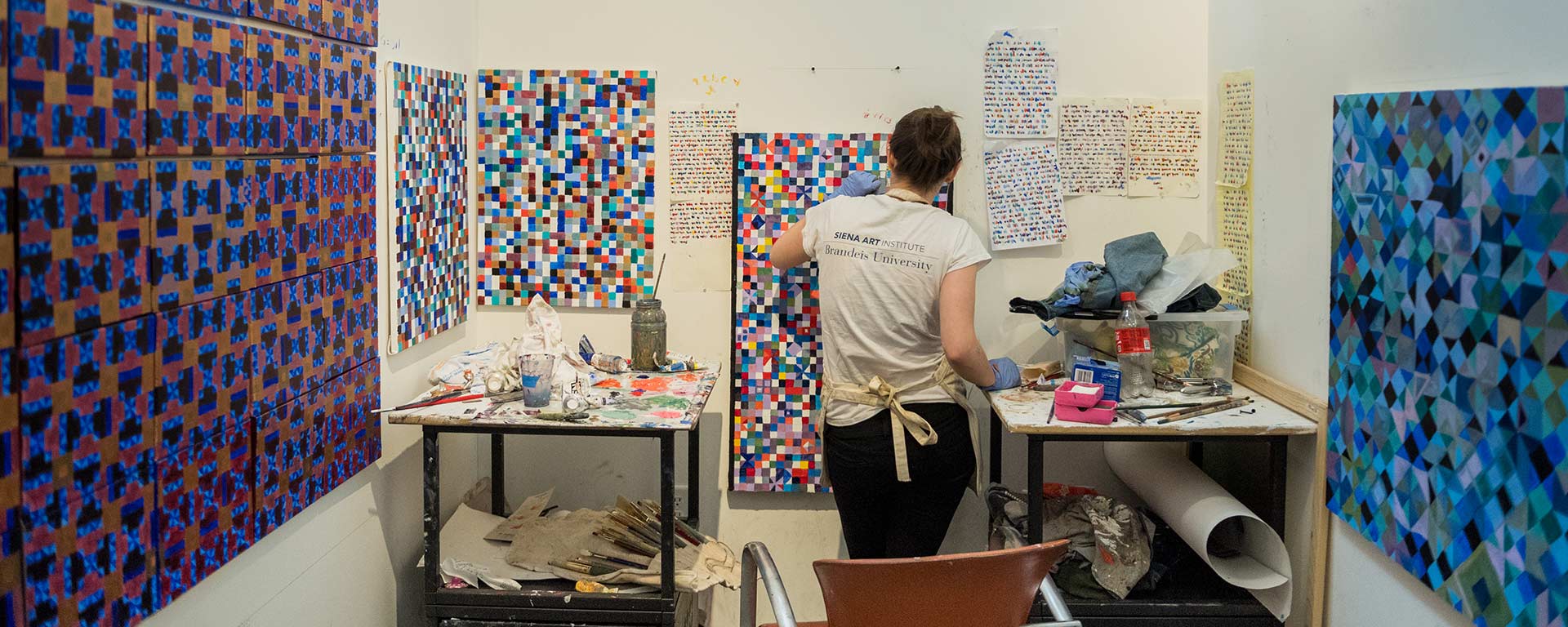 student painting at a wall surrounded by geometric artwork