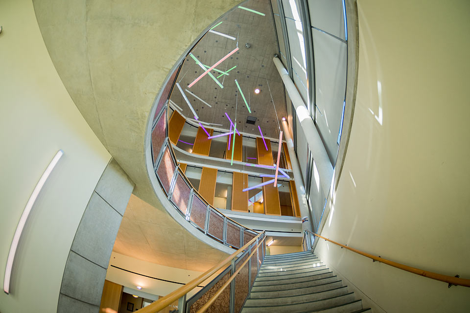 spiral staircase in the Mandel Center for Humanities illuminated by colorful neon cylinders
