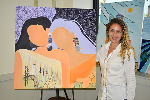 Natasha Frye stands next to a painting of two figures