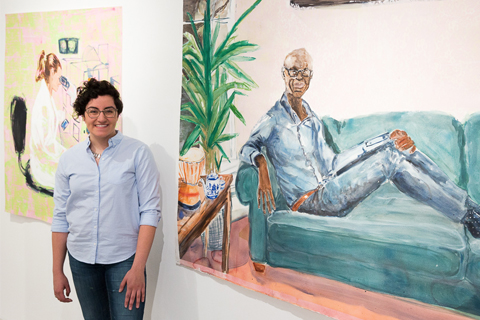 Sarah Valente stands in front of two of her paintings on paper