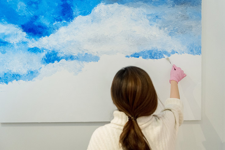 Female student facing a canvas painting with blue and white