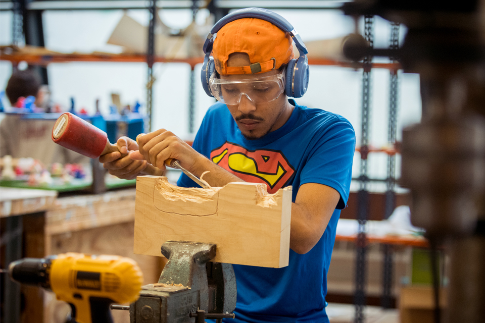 Student using a tool to carve wood in the sculpture studio in Goldman Schwartz