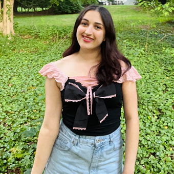 Portait of Ella Amouyal standing in front of greenery