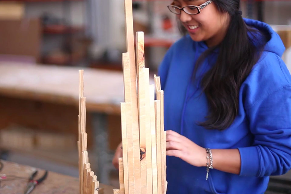 Student creating art with scrap wood