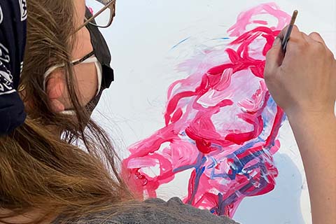Young painting a humanlike figure in pink