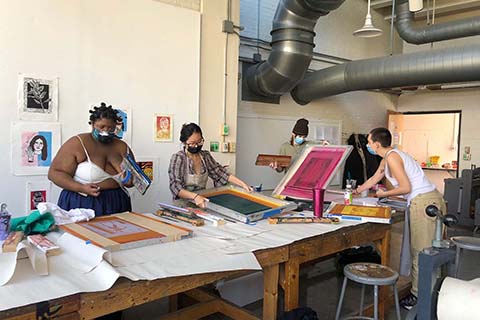 Group of four students around a table working on individual screen-prints