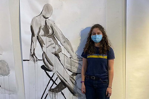 Troupe standing in front of their painting of a human figure leaning against a stool