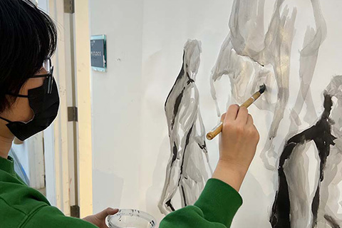 Li painting humanlike figures on a paper