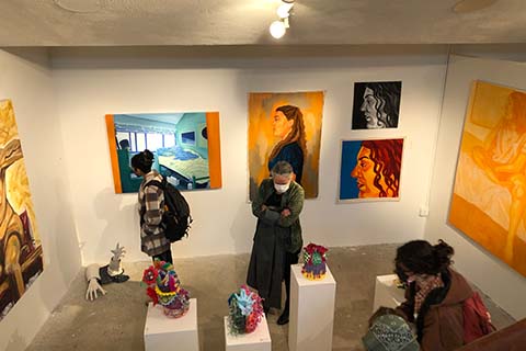 upper angle picture of students and faculty looking at artwork by Avery Donovan and Arline Bueno