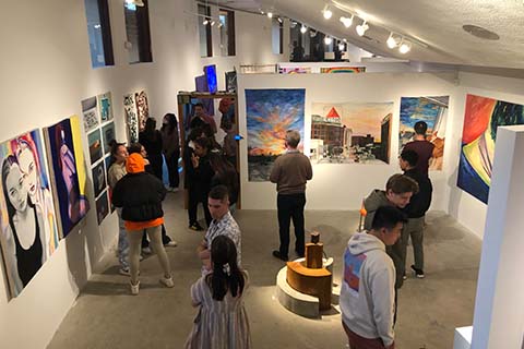 upper angle of students and faculty looking at artwork on the wall