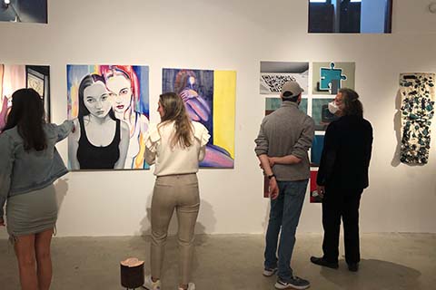 back view of students and faculty looking at artwork on the wall