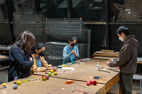 four students around a table and measuring yarn