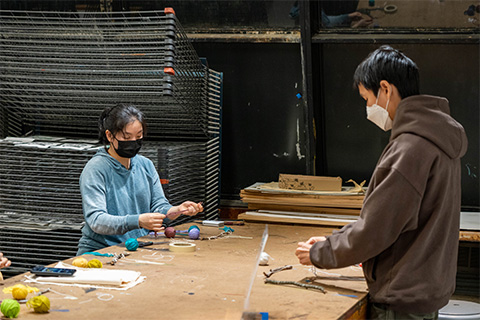 two students standing and holding yarn