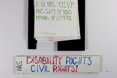 A hanging interactive installation made of paper and painted boards with a total size of five-feet tall by three-feet wide. This is an activist piece of artwork meant to educate the viewer on various disabilities. A stationary painted board at the bottom of the artwork declares, “DISABILITY RIGHTS ARE CIVIL RIGHTS!” Above this text are multiple large paper cards the viewer can shift through to read informative facts about various disabilities.