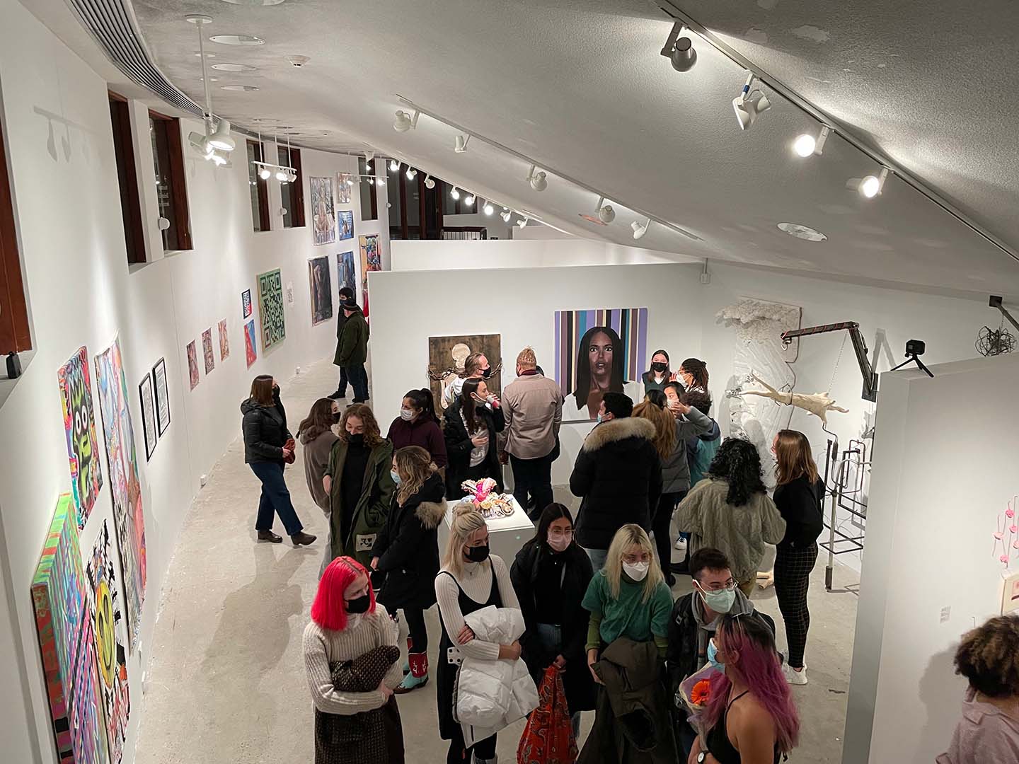Students and guests standing and talking in front of artwork on the walls