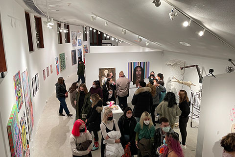 Students and guests standing and talking in front of artwork on the walls