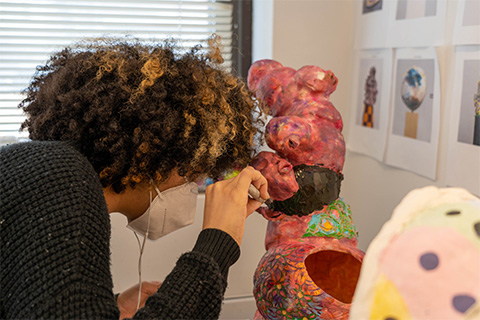 Angled view of Bueno working on a pink sculpture with delicacy