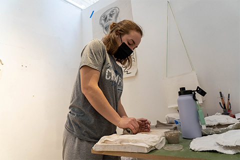 lower angle view of Moran kneading clay on a table