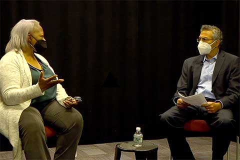 Wearing masks, Carol Anderson and Rajesh Sampath sit on a stage
