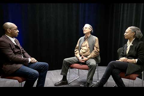 three people sitting in chairs, talking