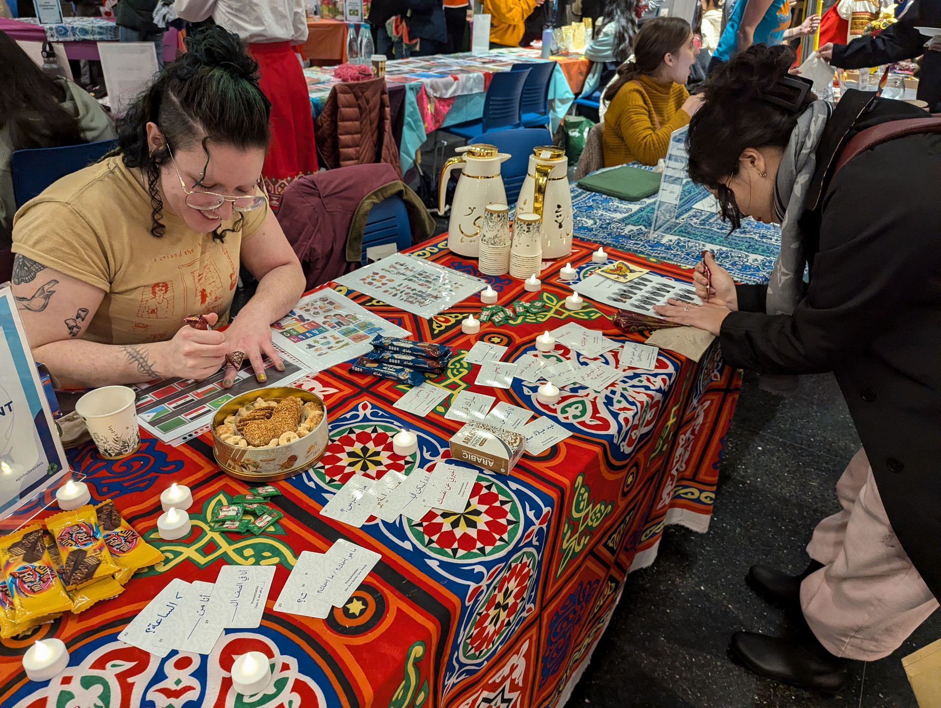 Student drawing Henna on hands at the Global Bazaar