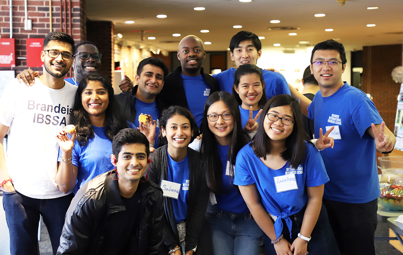 12 leadership fellows (students) in blue shirts posing and smiling for the camera during new student orientation